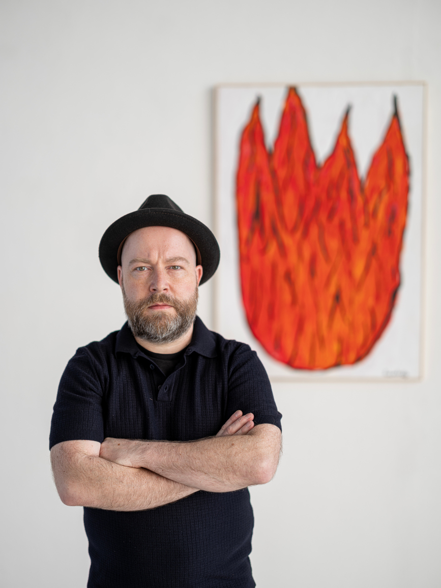 Ivan Summersky, German Ignorant Artist, vor einem Feuerbild aus der Serie BURN!